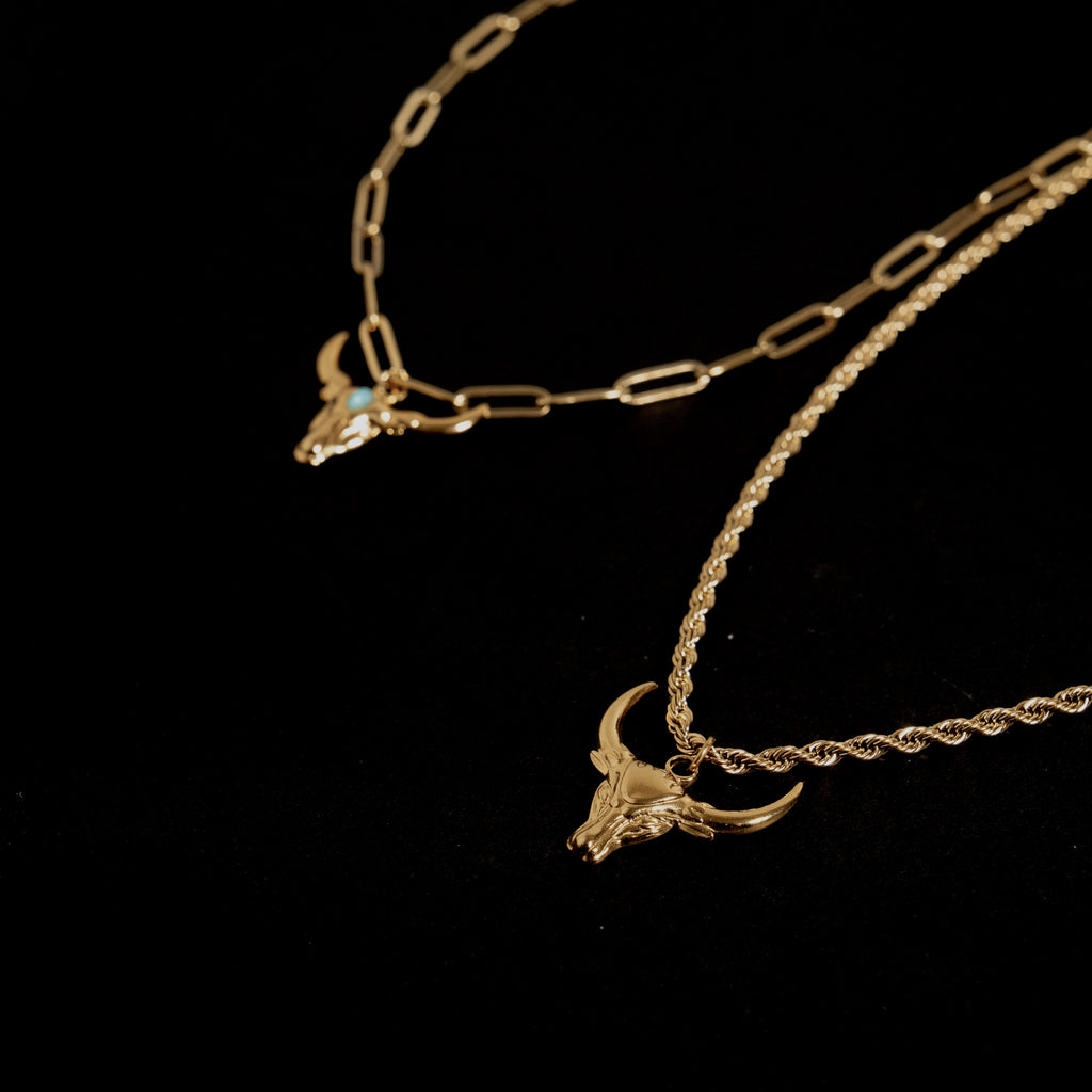 Gold necklace with bull head pendants on a black background