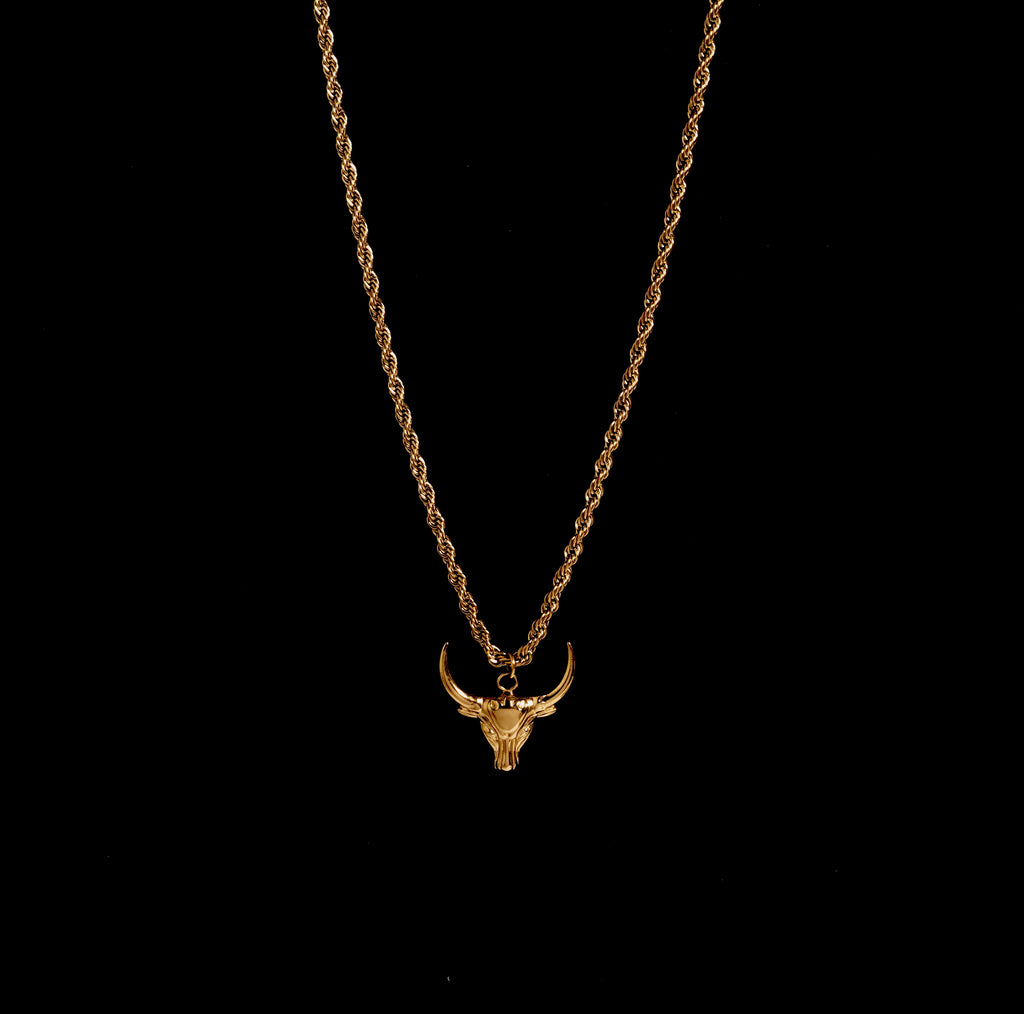 Gold necklace with a bull head pendant on a black background